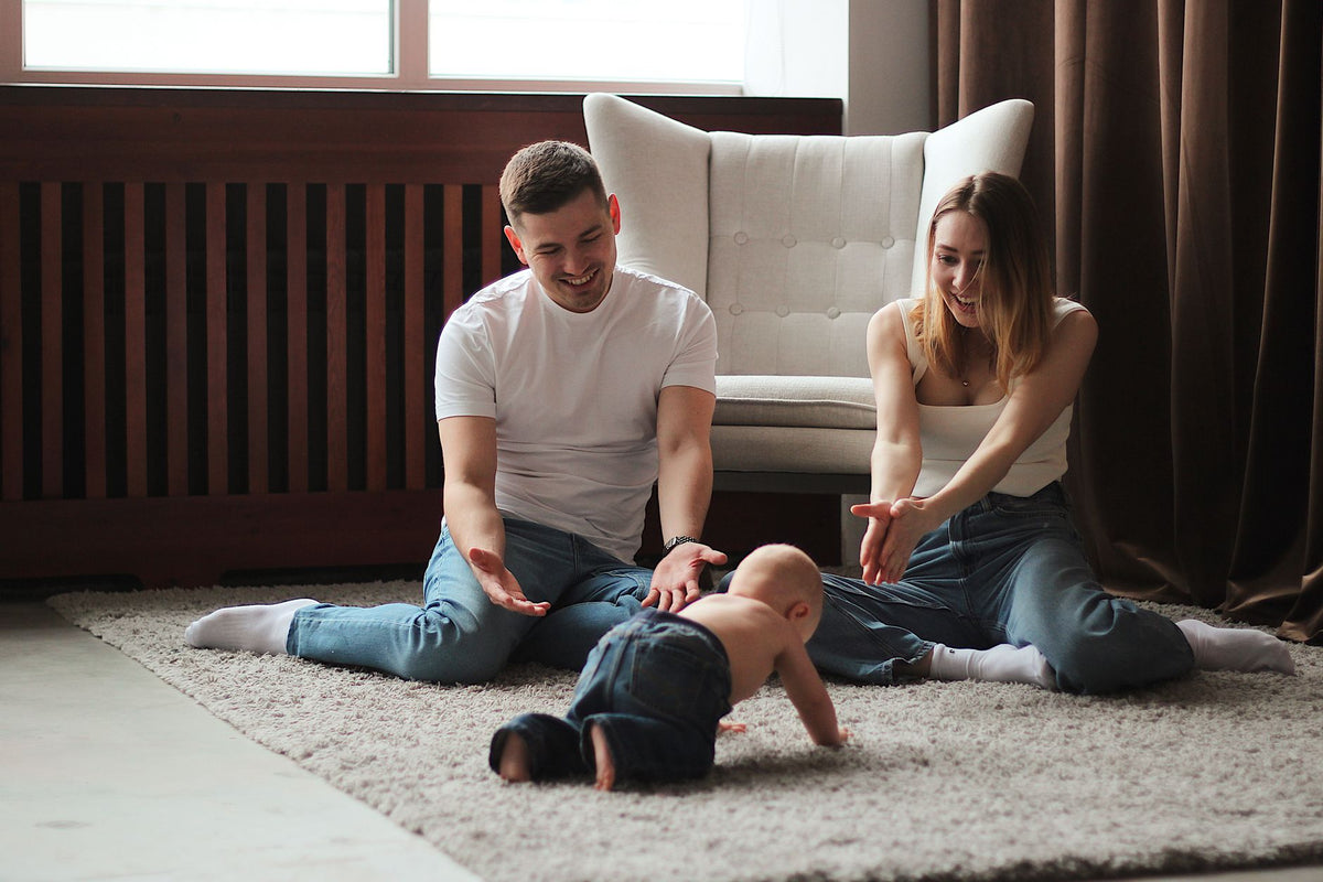 Young family enjoys playtime with their baby on a cozy living room rug, fostering a bonding moment.