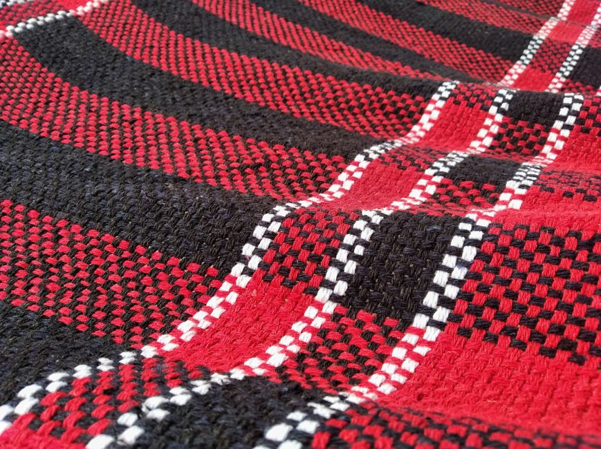 Detailed close-up of a red and black plaid fabric with a textured woven pattern.