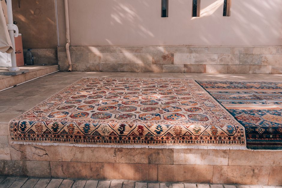 Elegant traditional rugs displayed in a sunlit Bukhara courtyard.