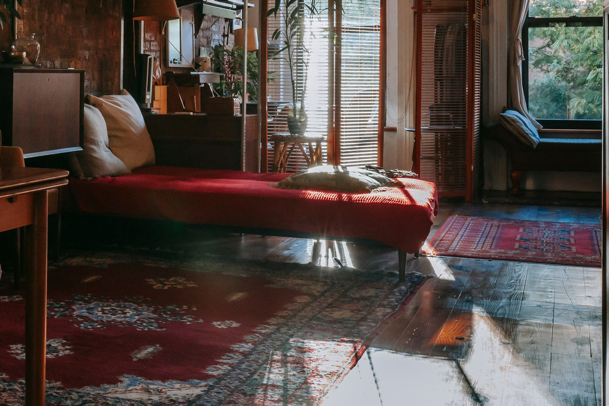 Interior of stylish bedroom with vintage wooden furniture decorated with antique carpets and green potted plants