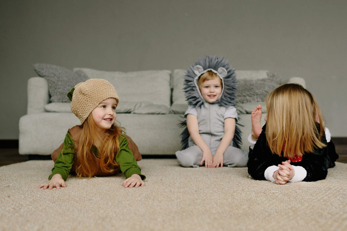 Three children having fun in animal costumes on a living room floor, showcasing playful joy.