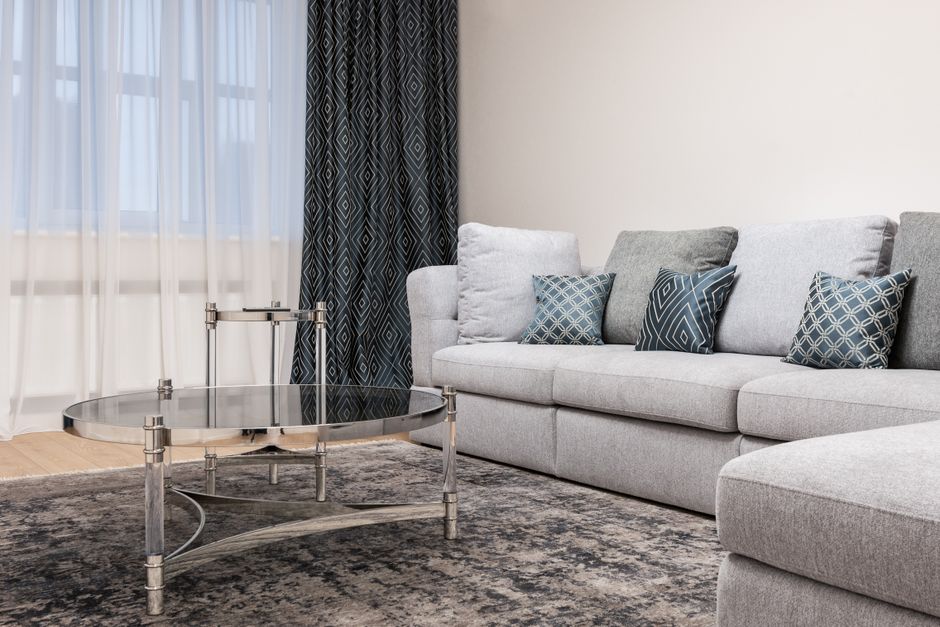 Couch with decorative cushions against metal and glass tables on rug in light house room