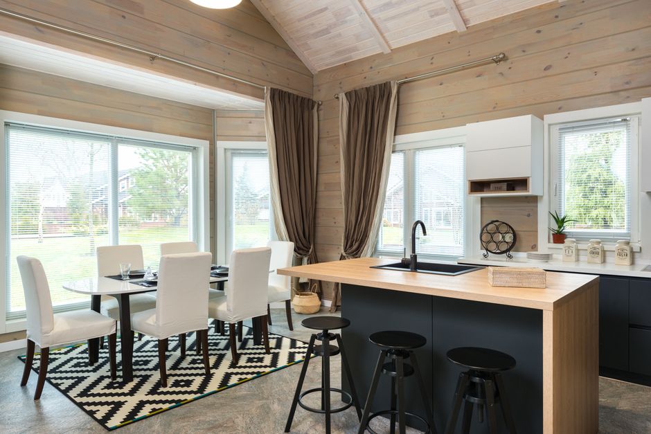 Contemporary convenient kitchen with bar chairs at counter near dining table and chairs on carpet in suburb house with panoramic windows